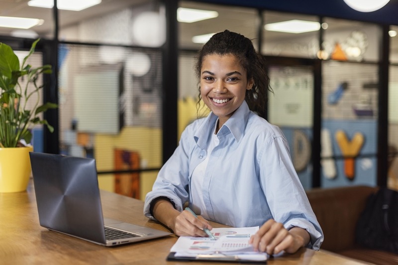 smiley woman working with laptop papers office